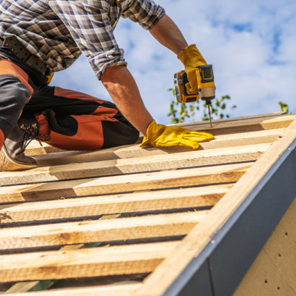 DIY RentalsA contractor using a power drill to install framing for a roof